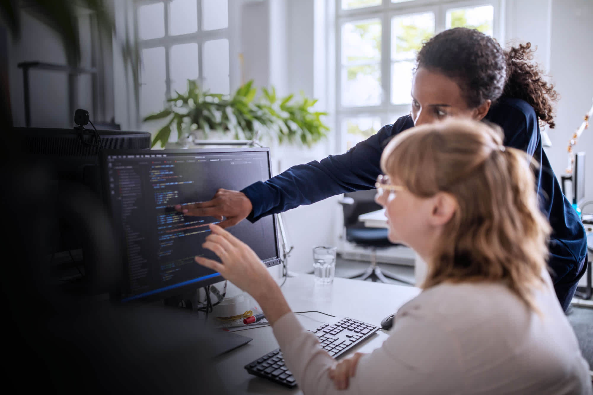 One colleague shows another how to do something on their computer