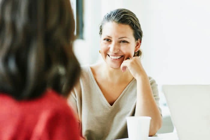 A woman in a white shirt listens during a meeting.