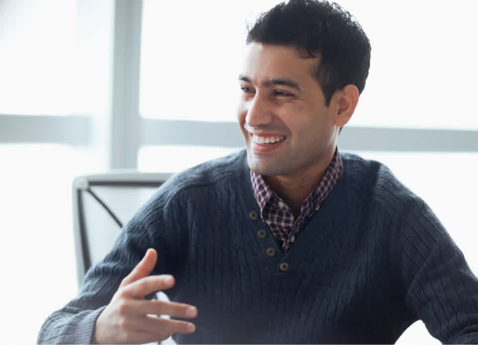 A man in a sweater smiles during a business meeting.