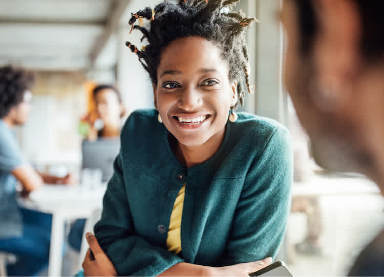 Woman in a blue shirt listening and smiling.