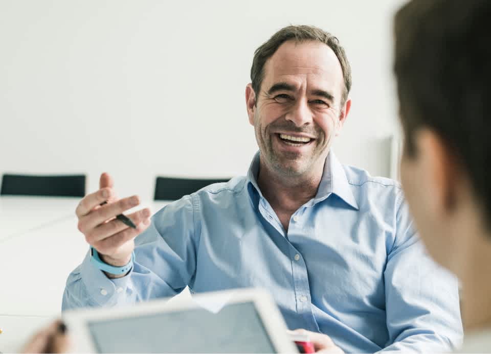 A man in a meeting smiles